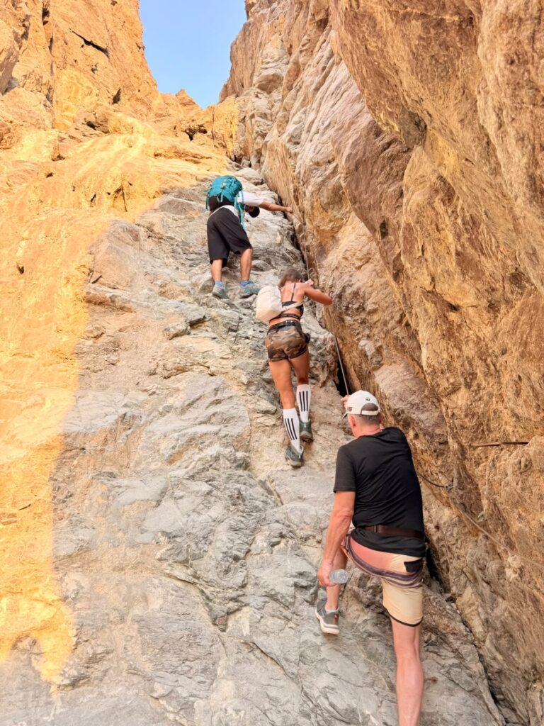 Hikers climbing a rocky section of the Wadi Daftah trail in the UAE